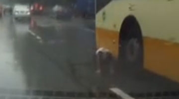 实拍男孩马路中央玩滑板 遭客车卷入车底险丧生